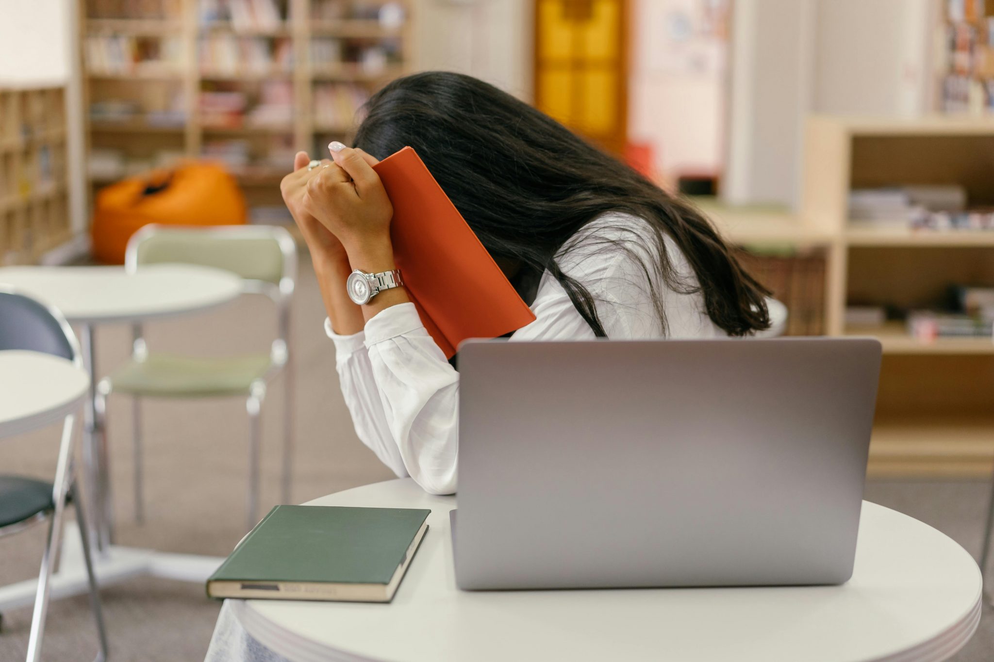 Una joven tímida cubriéndose la cara con un libro, representando la dificultad para interactuar socialmente, característica de la ansiedad social